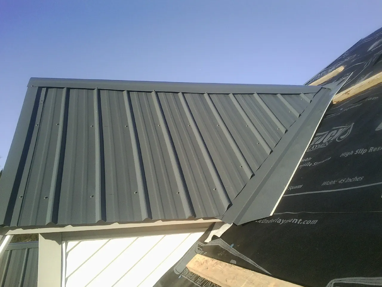 Gray metal roof panels going on over a garage gable in New Franken