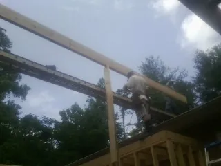 Carpenter setting a ridge beam over a new addition frame — Ice Dam Removal by Roofing Brothers in New Franken