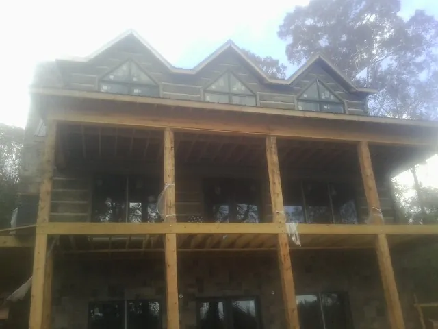 Dormers and porch framing on a large log home under construction — Roof Coating work by our crew in New Franken