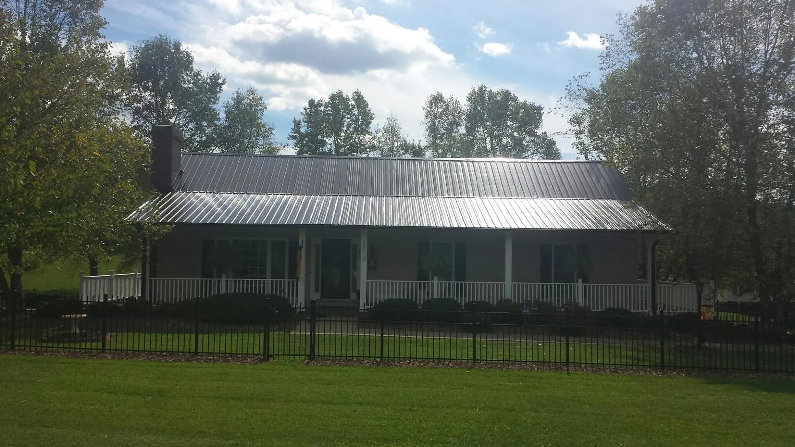 Gray metal roof on a brick ranch with a full width front porch — Gutter Guard Installation work by our crew in New Franken