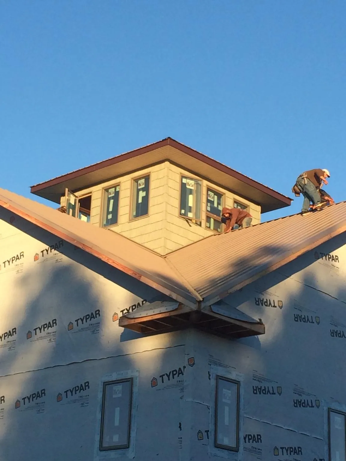 Roofers working around a rooftop cupola on a new metal roof at sunset — Roof Waterproofing in New Franken by Roofing Brothers
